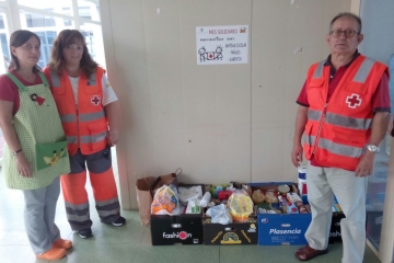 La directora del centro posa con los miembros de Cruz Roja y los alimentos.